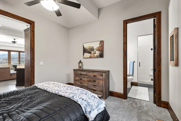 Bedroom featuring light carpet, connected bathroom, and a ceiling fan