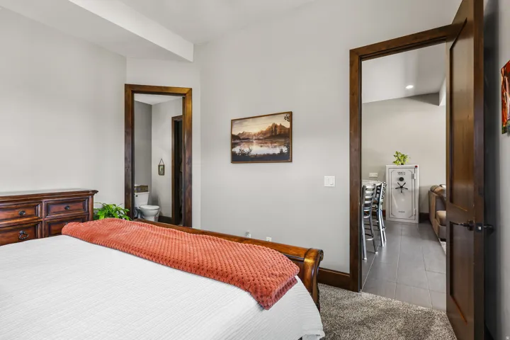 Bedroom featuring connected bathroom, light carpet, and light tile patterned flooring