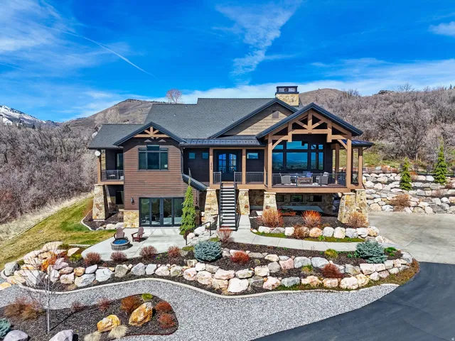 Rear view of property featuring stone siding, a chimney, a mountain view, french doors, and covered porch