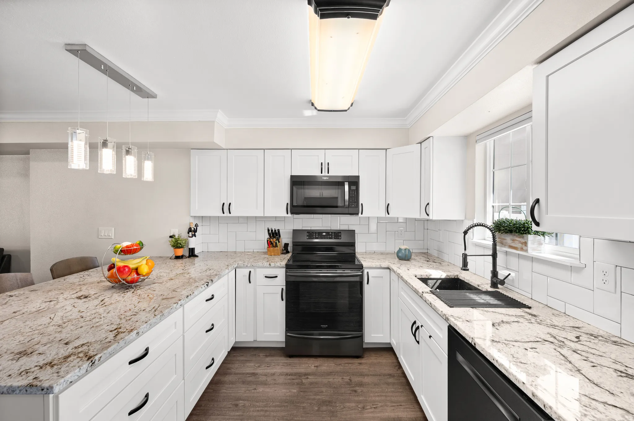 Kitchen with backsplash, a peninsula, white cabinetry, black stainless steel appliances, and granite counter tops