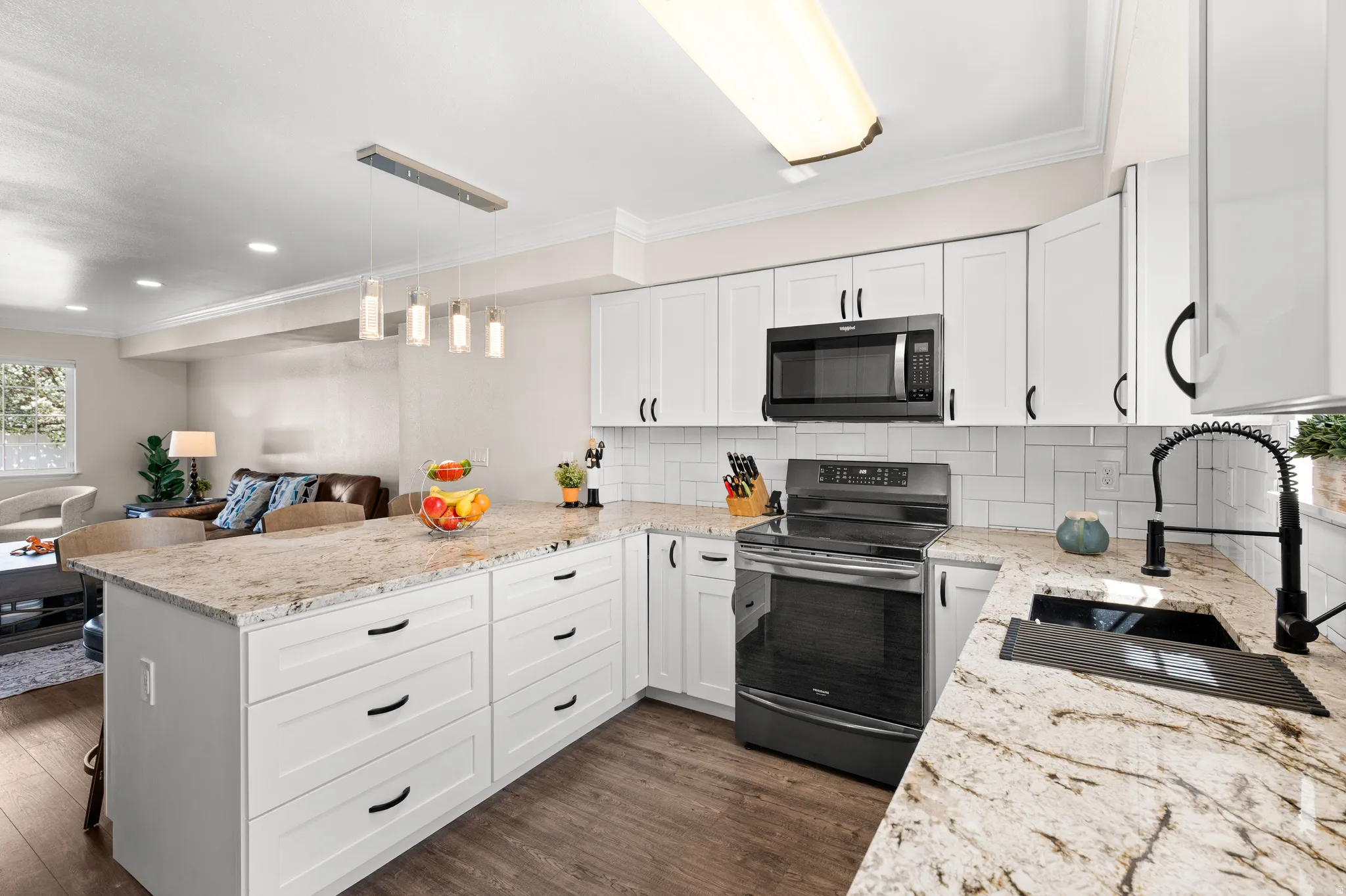 Kitchen with backsplash, a peninsula, white cabinetry,black stainless steel appliances, and granite counter tops and open floor plan