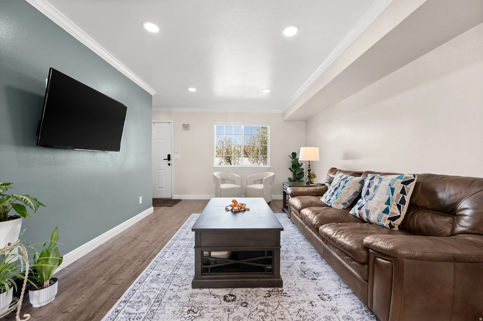 Living room with crown molding, new LVP floors, and recessed lighting.