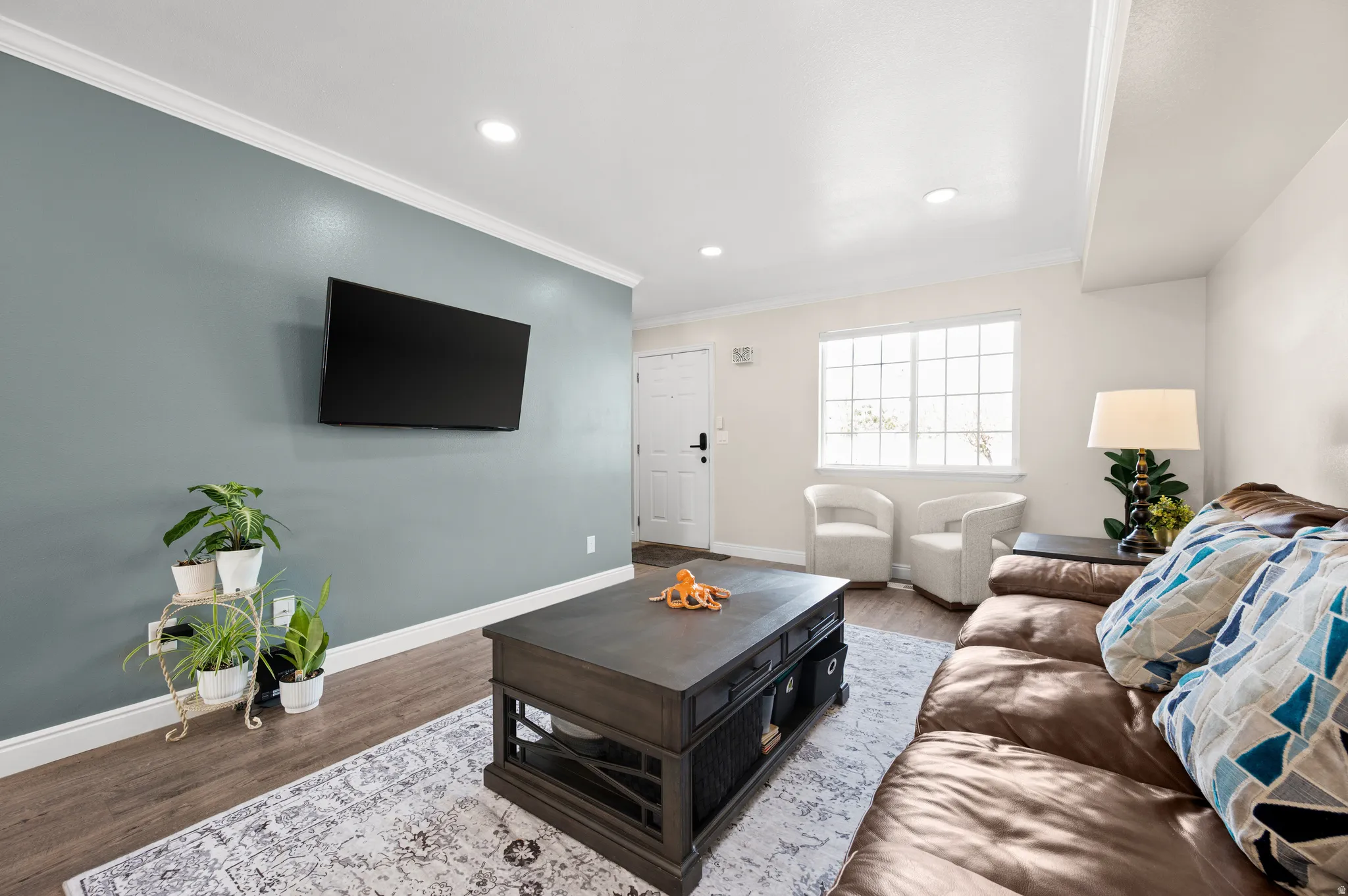 Living room with crown molding, new LVP floors, and recessed lighting.