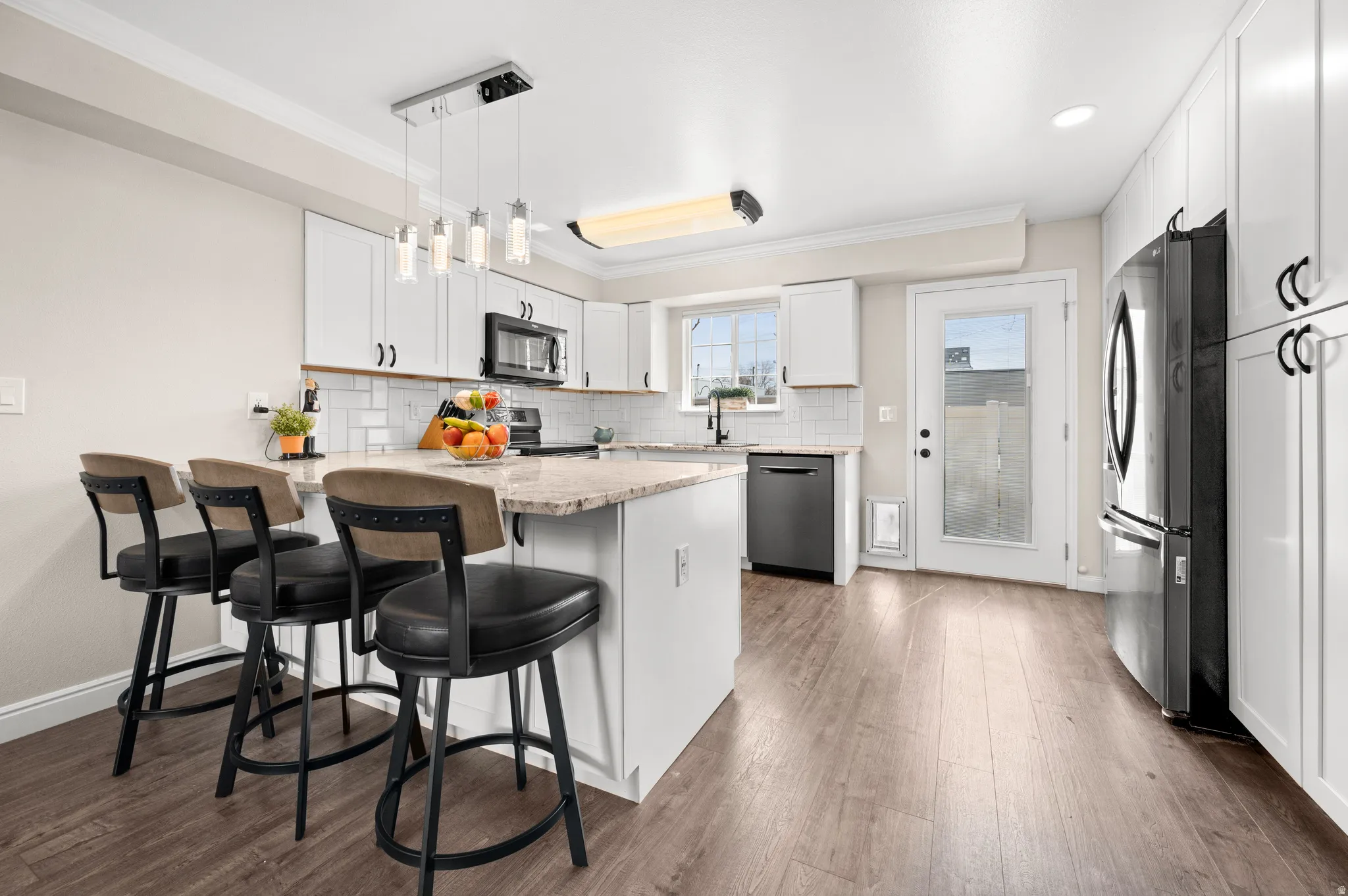 Kitchen featuring white cabinetry, a giant custom peninsula, granite counter tops and black stainless steel appliances.