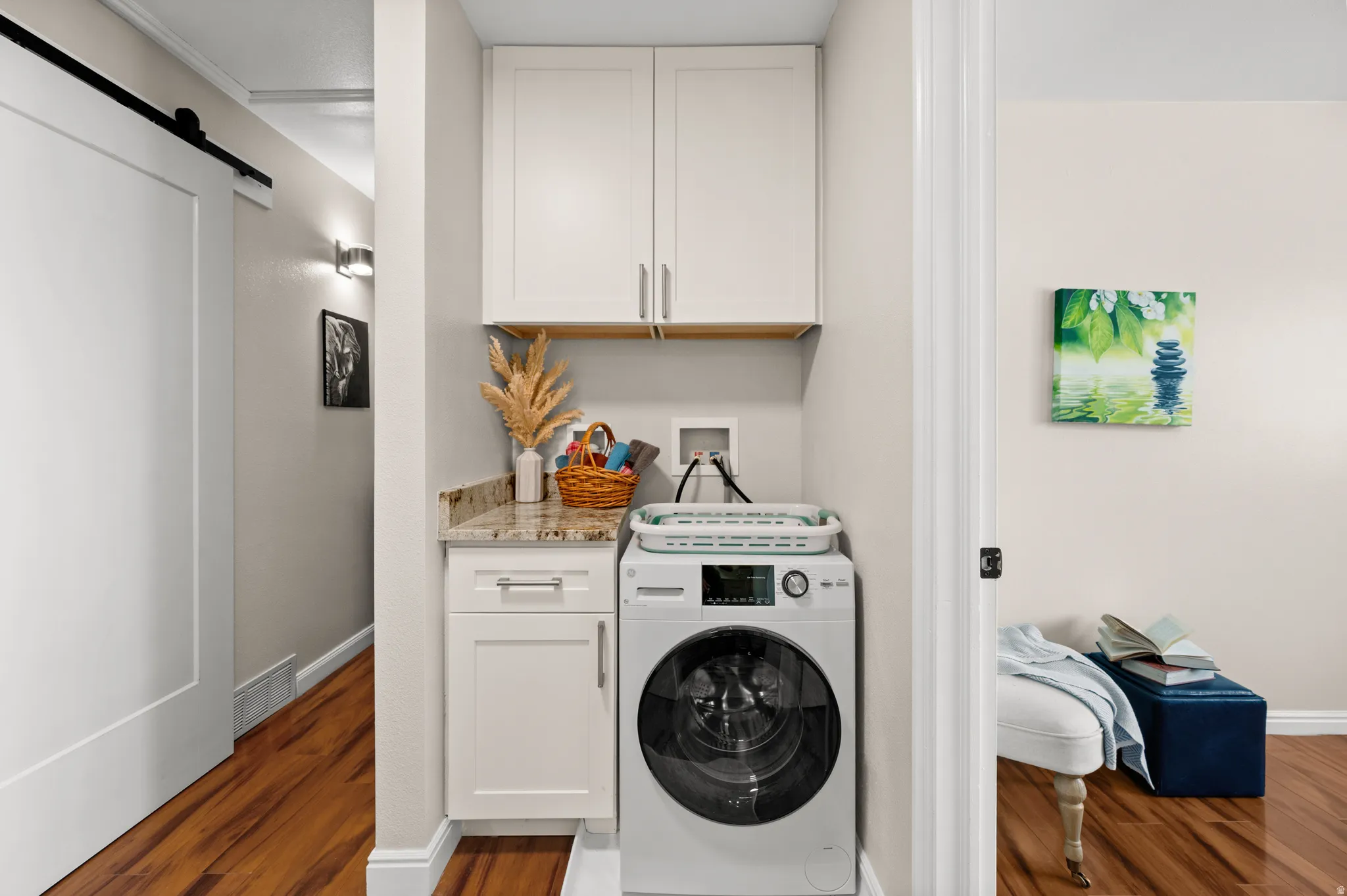 Laundry area with cabinet space,  featuring an all-in-one washer / drye  a custom barn door to master bedroom