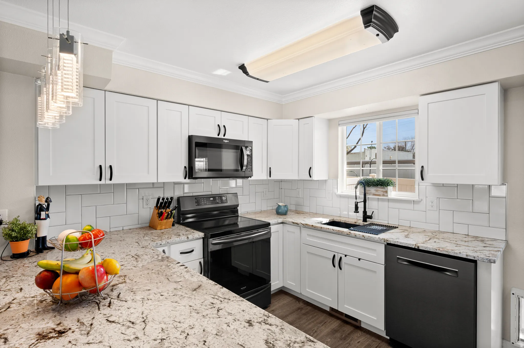 Kitchen with backsplash, a peninsula, white cabinetry, black stainless steel appliances, and granite counter tops