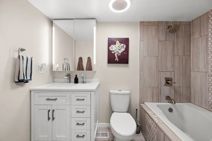 Full bathroom with tiled shower, deep soaker tub and vanity