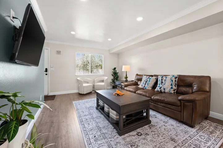 Living room with crown molding, new LVP wood floors, and recessed lighting