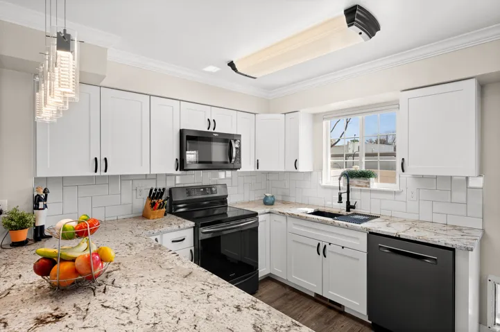 Kitchen with backsplash, a peninsula, white cabinetry, black stainless steel appliances, and granite counter tops