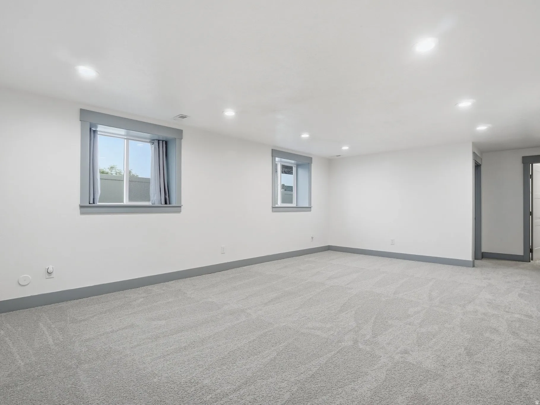 Empty room with light carpet and recessed lighting