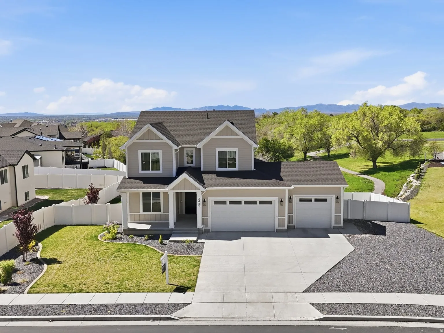 View of front of property with driveway, an attached garage, a residential view, roof with shingles, and a mountain view