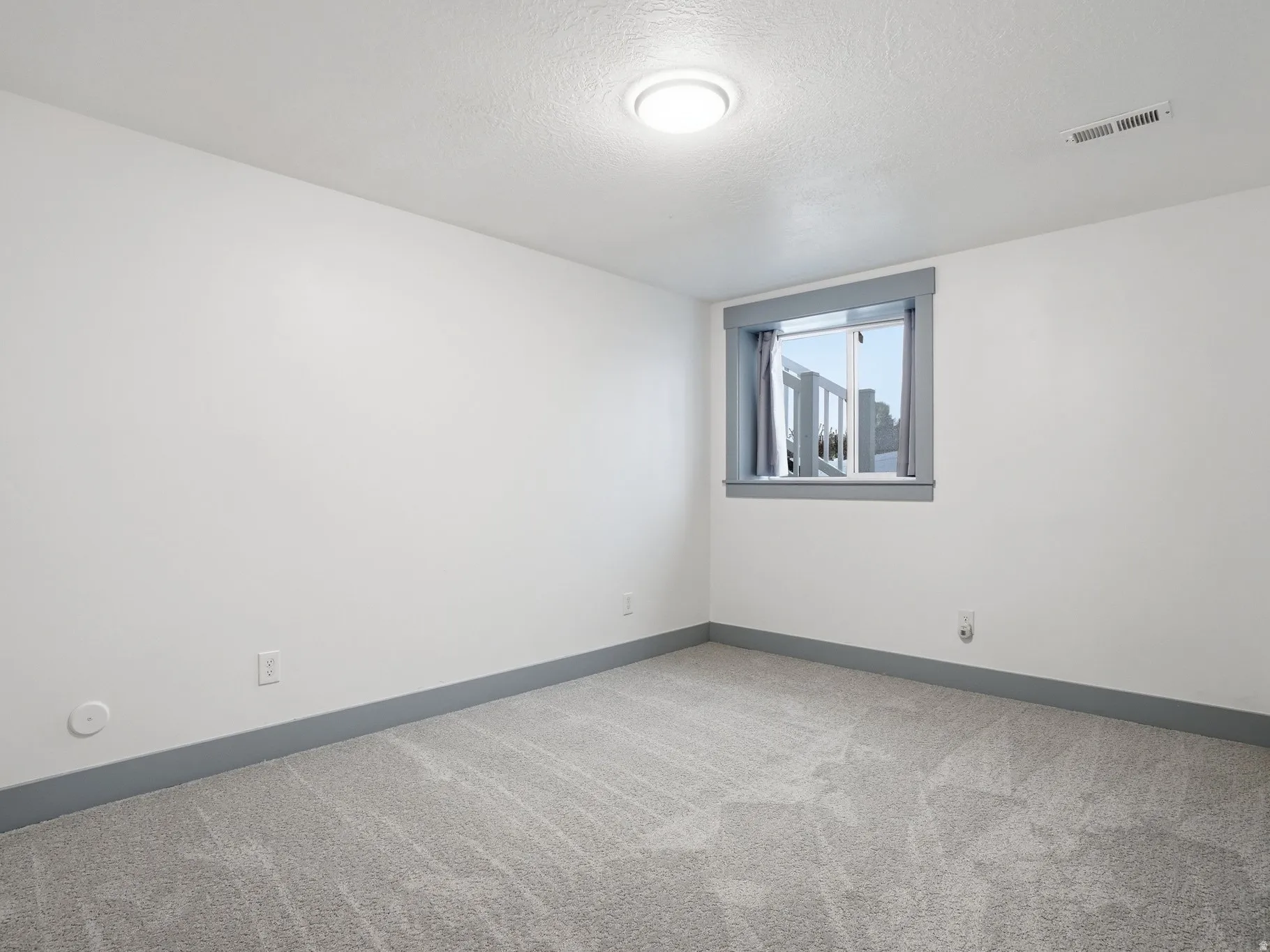Unfurnished room featuring light carpet and a textured ceiling