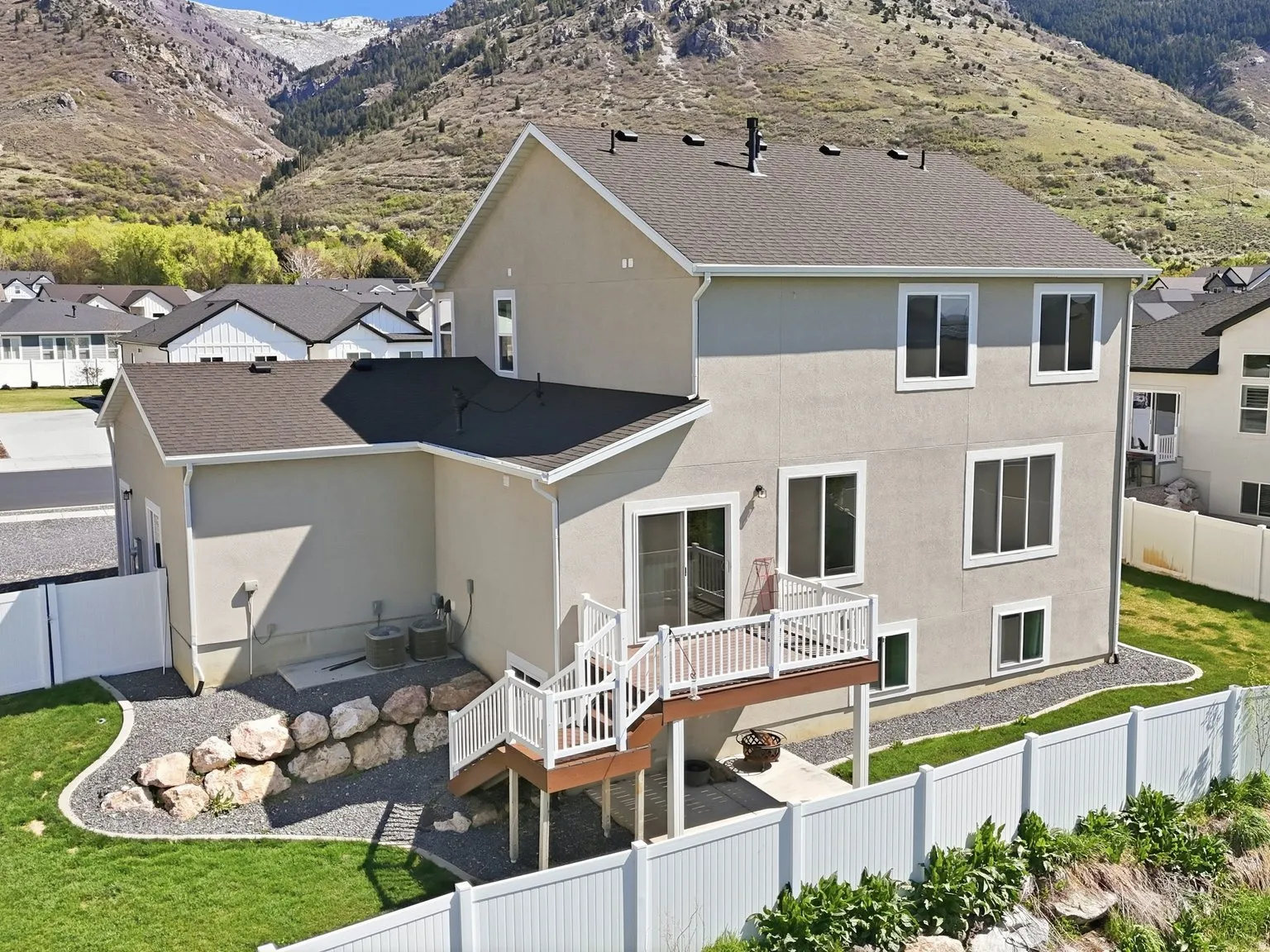 Rear view of house with a fenced backyard, stucco siding, a deck with mountain view, a patio area, and a residential view