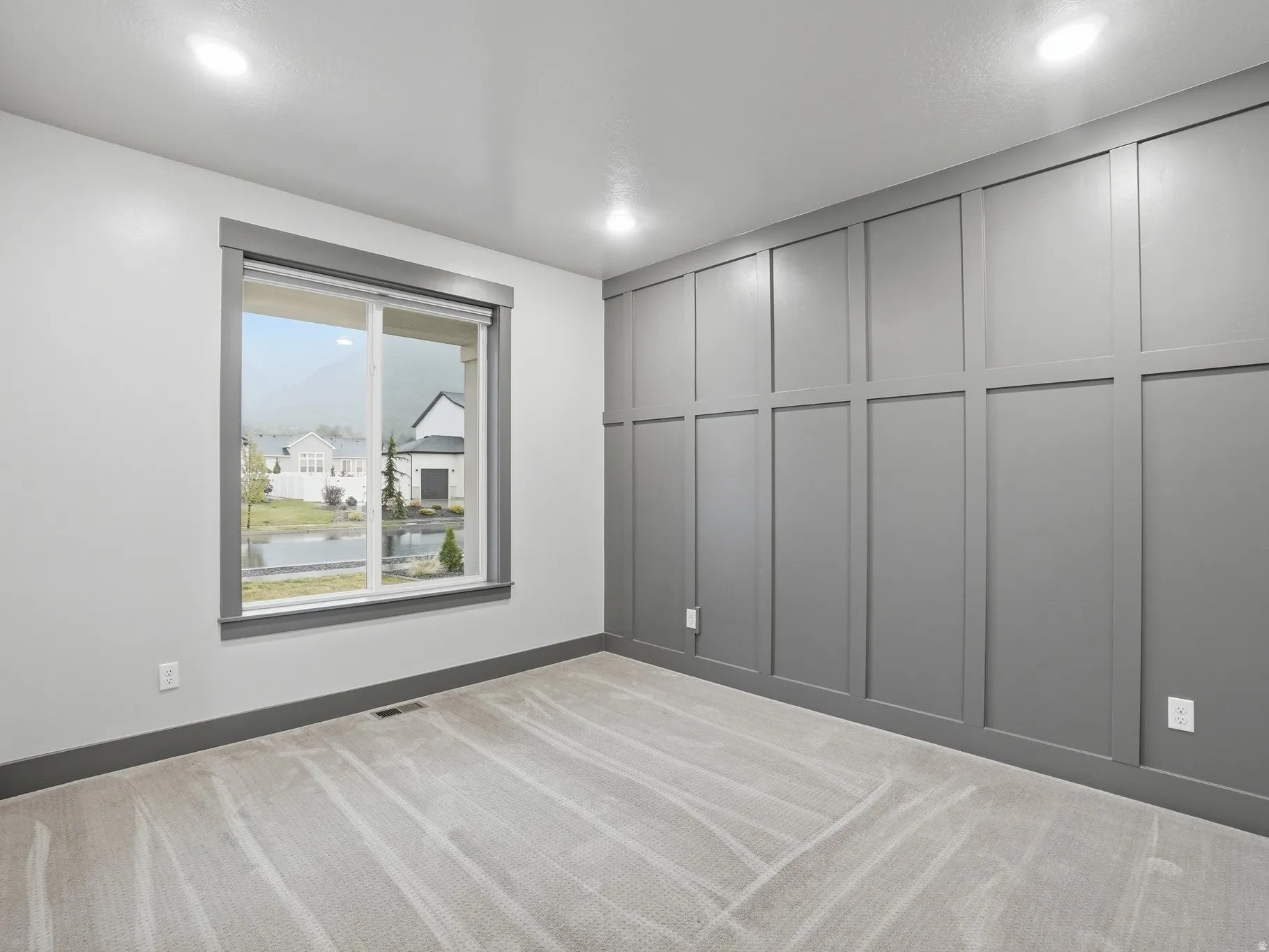 Unfurnished room with light colored carpet, a decorative wall, and a water view