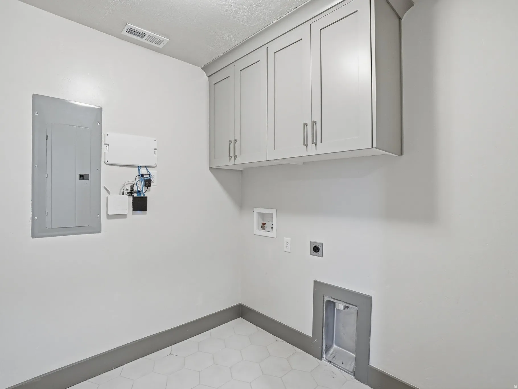 Laundry room with electric panel, hookup for an electric dryer, cabinet space, and hookup for a washing machine