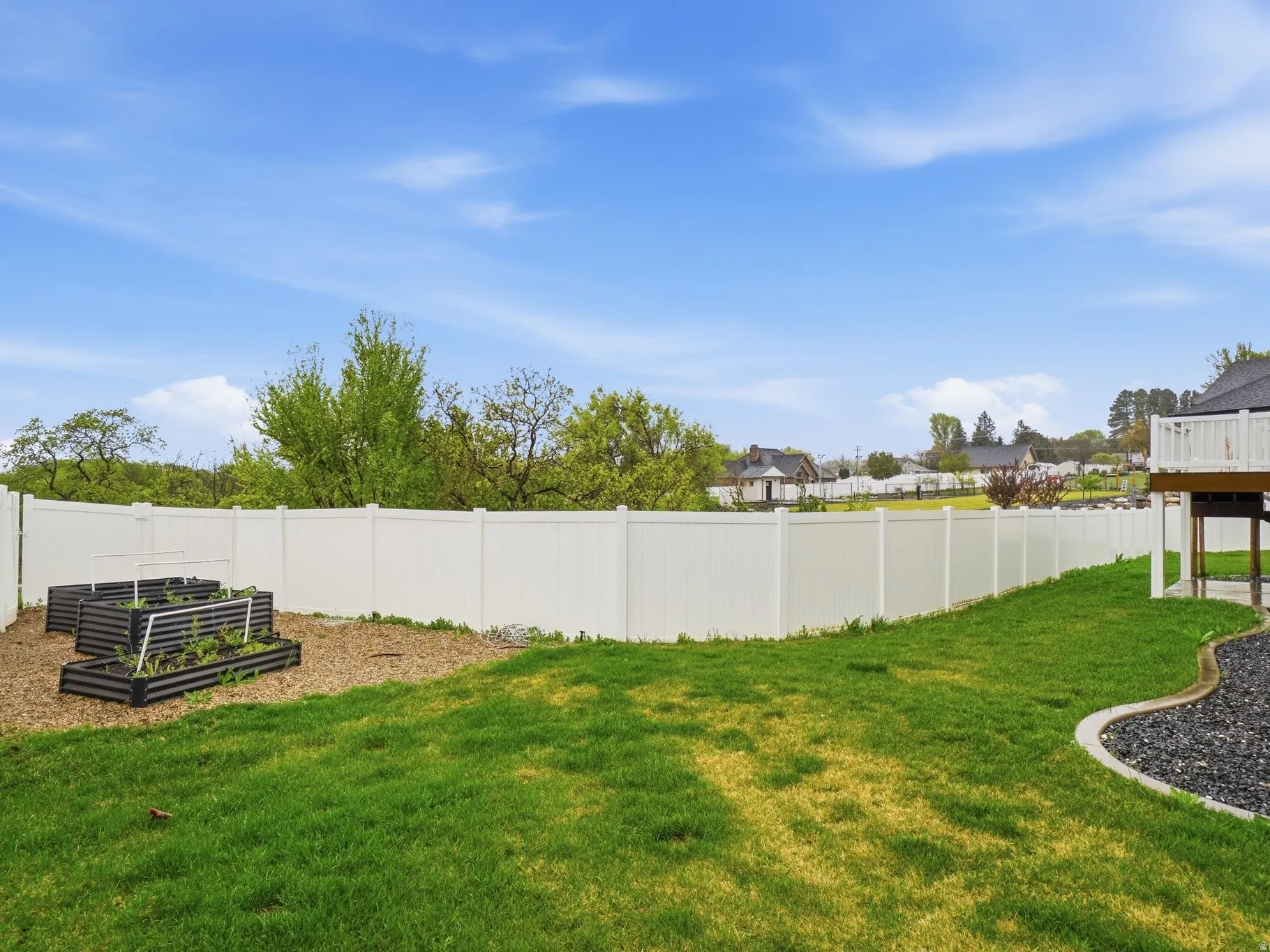 Fenced backyard featuring a garden, a residential view, and a wooden deck