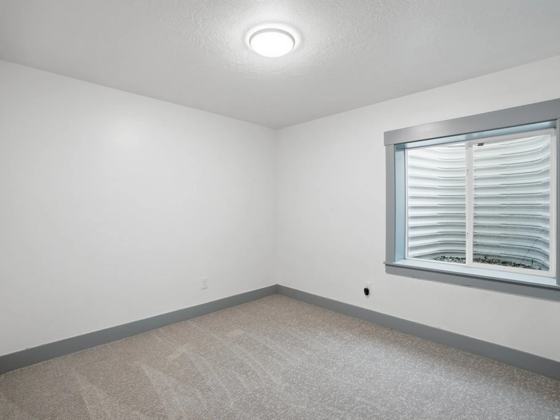Carpeted spare room with baseboards and a textured ceiling