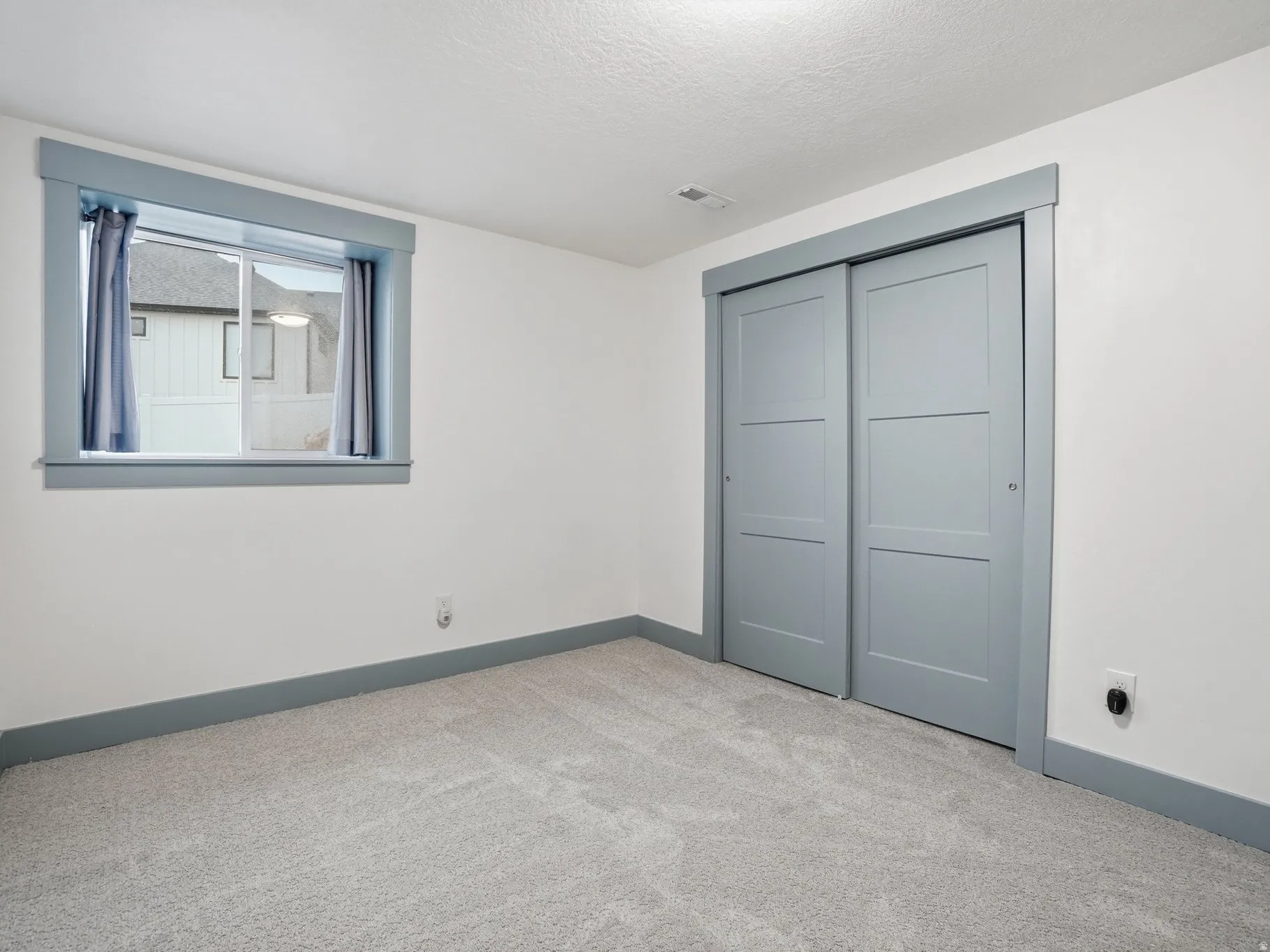 Unfurnished bedroom featuring light colored carpet, a closet, and a textured ceiling