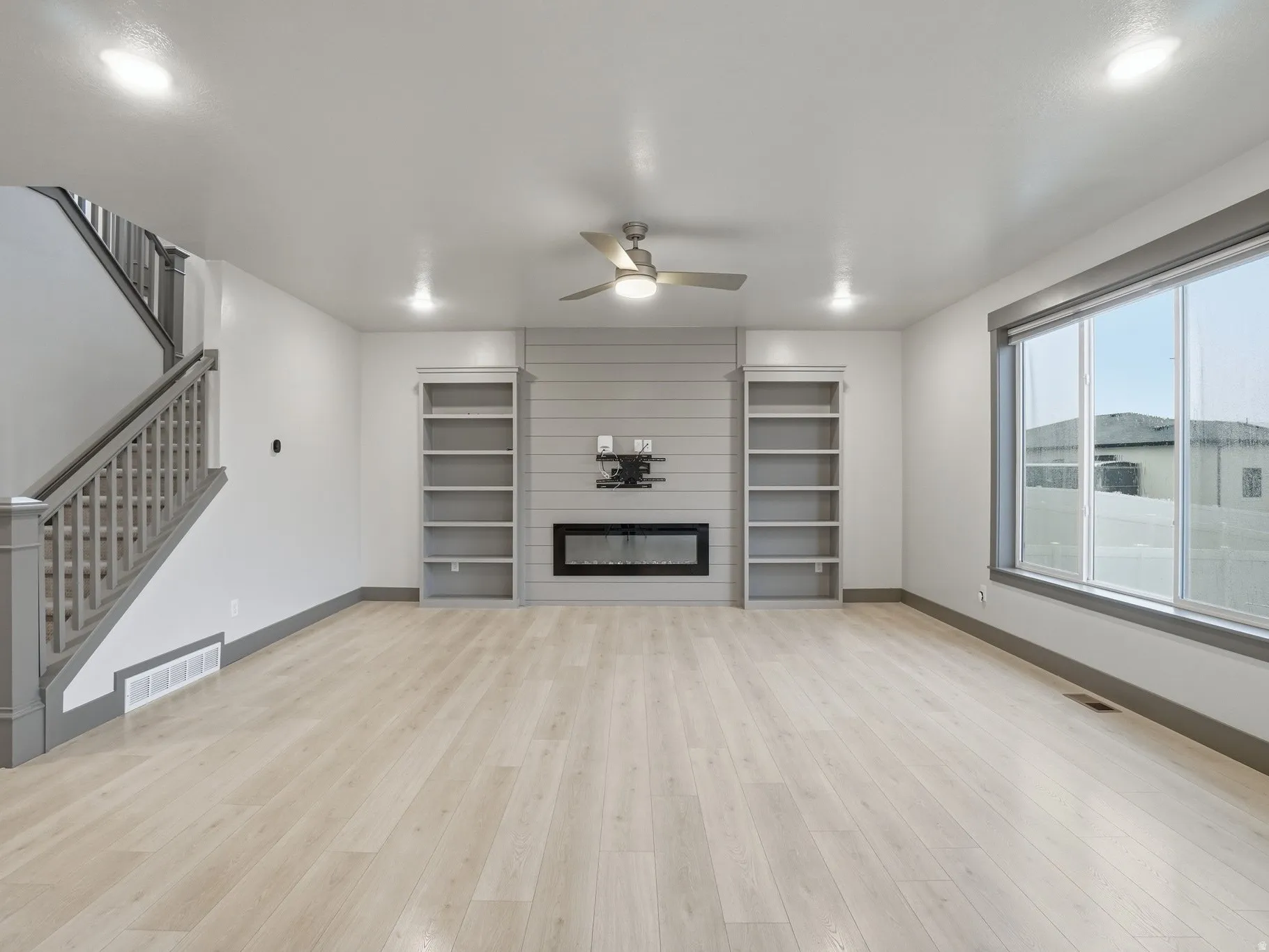 Unfurnished living room featuring ceiling fan, light wood-style floors, and a large fireplace