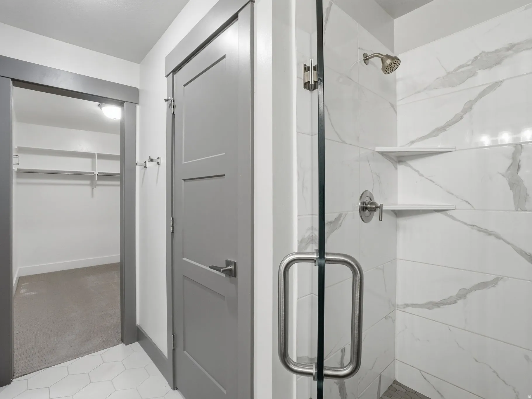 Full bath with a marble finish shower, a walk in closet, and light colored carpet