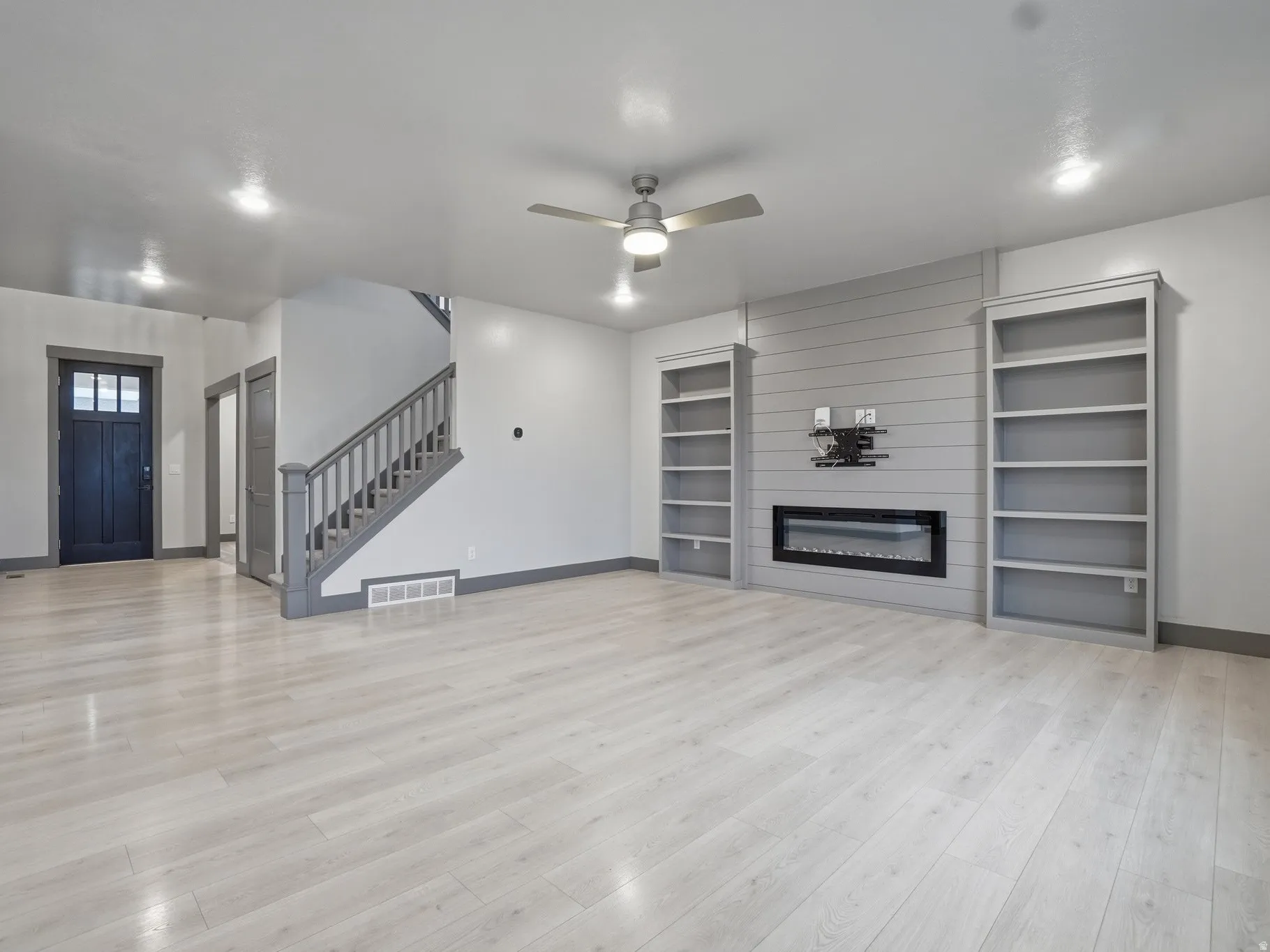 Unfurnished living room with a ceiling fan, a fireplace, and light wood finished floors