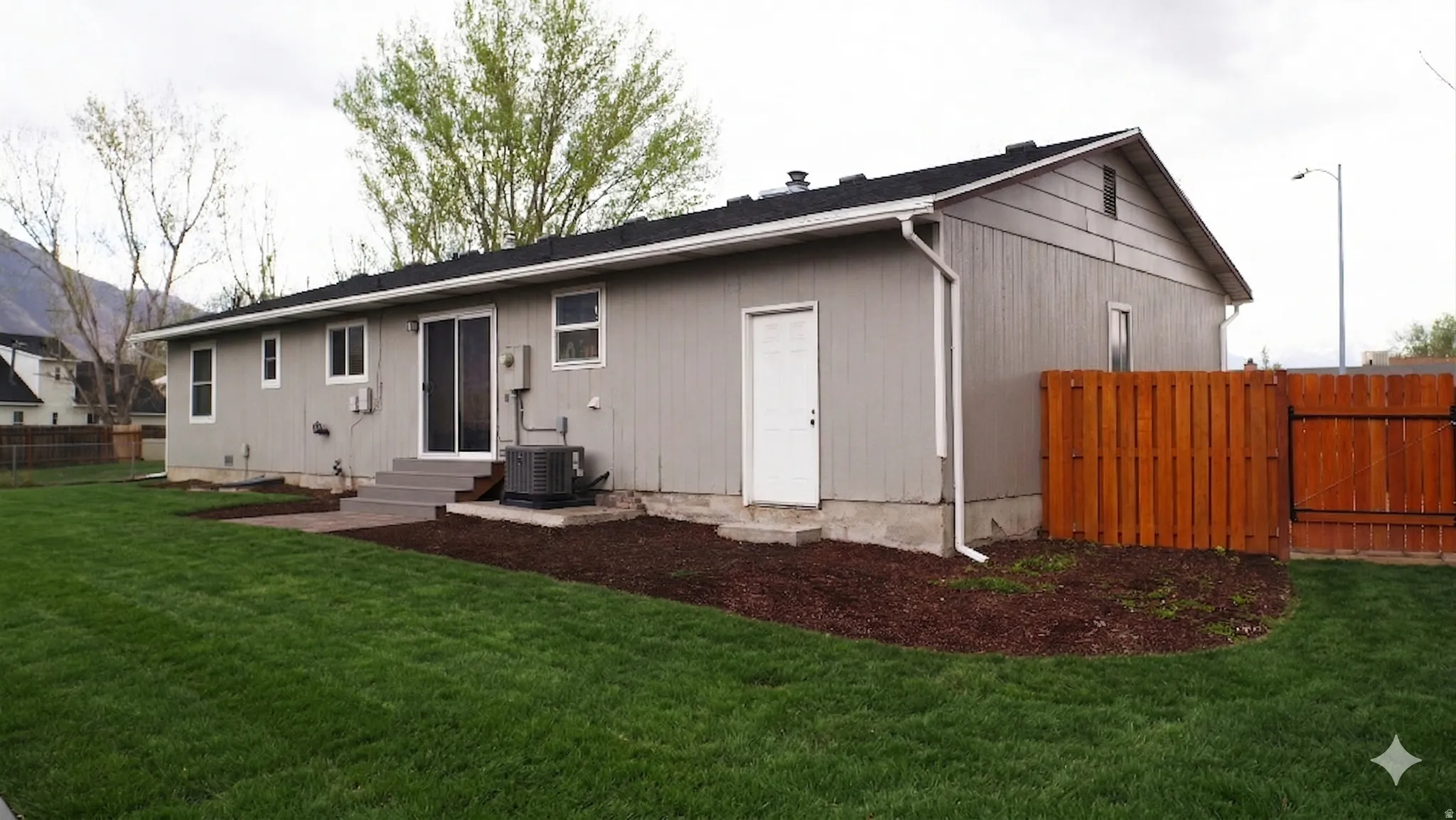 Back of house with entry steps and a gate with Ai grass