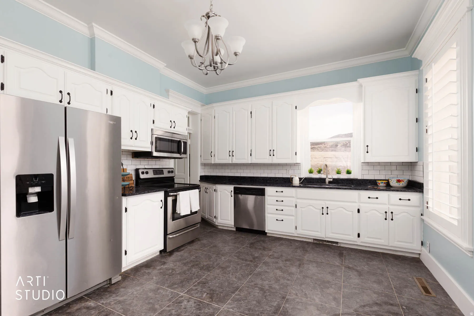 Kitchen featuring stainless steel appliances, white cabinetry, a chandelier, crown molding, and backsplash