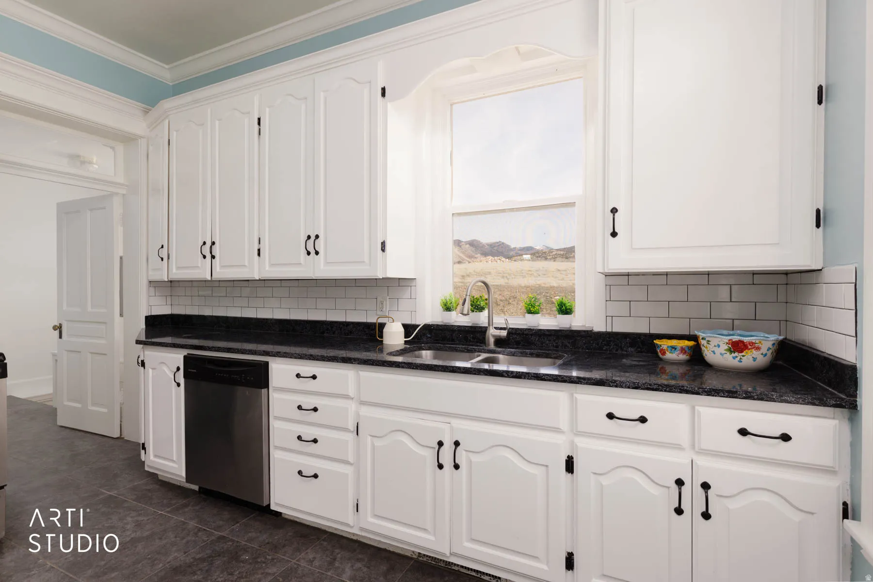 Kitchen with white cabinets, dishwasher, decorative backsplash, dark stone countertops, and ornamental molding