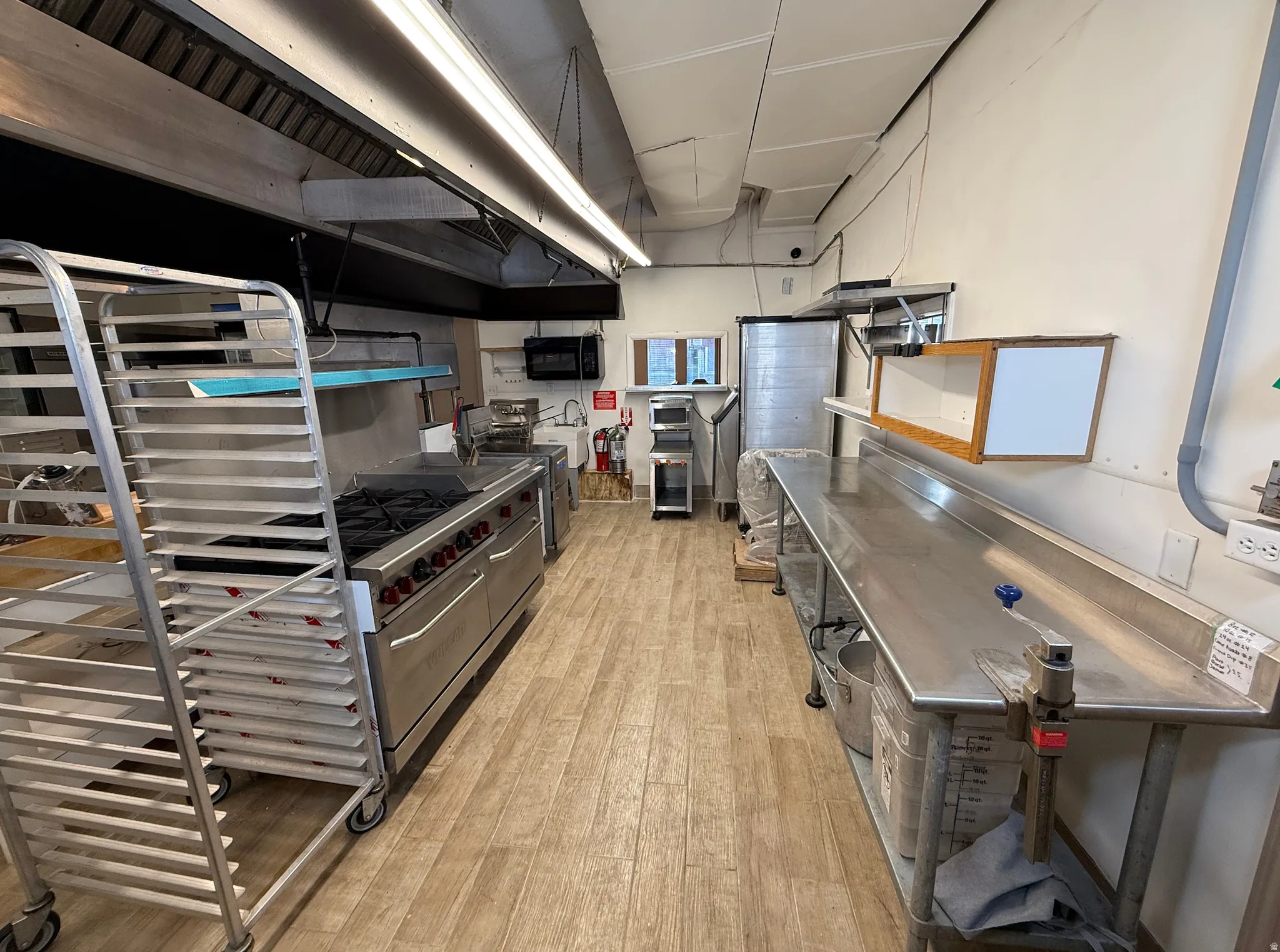 Kitchen featuring ventilation hood, stainless steel counters, black microwave, and double oven range
