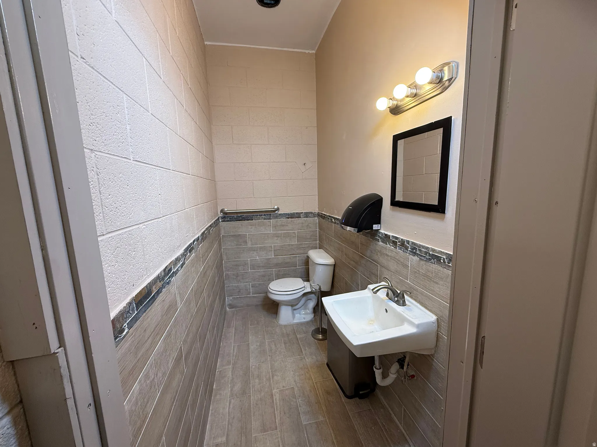 Bathroom featuring tile walls, a wainscoted wall, and wood finished floors