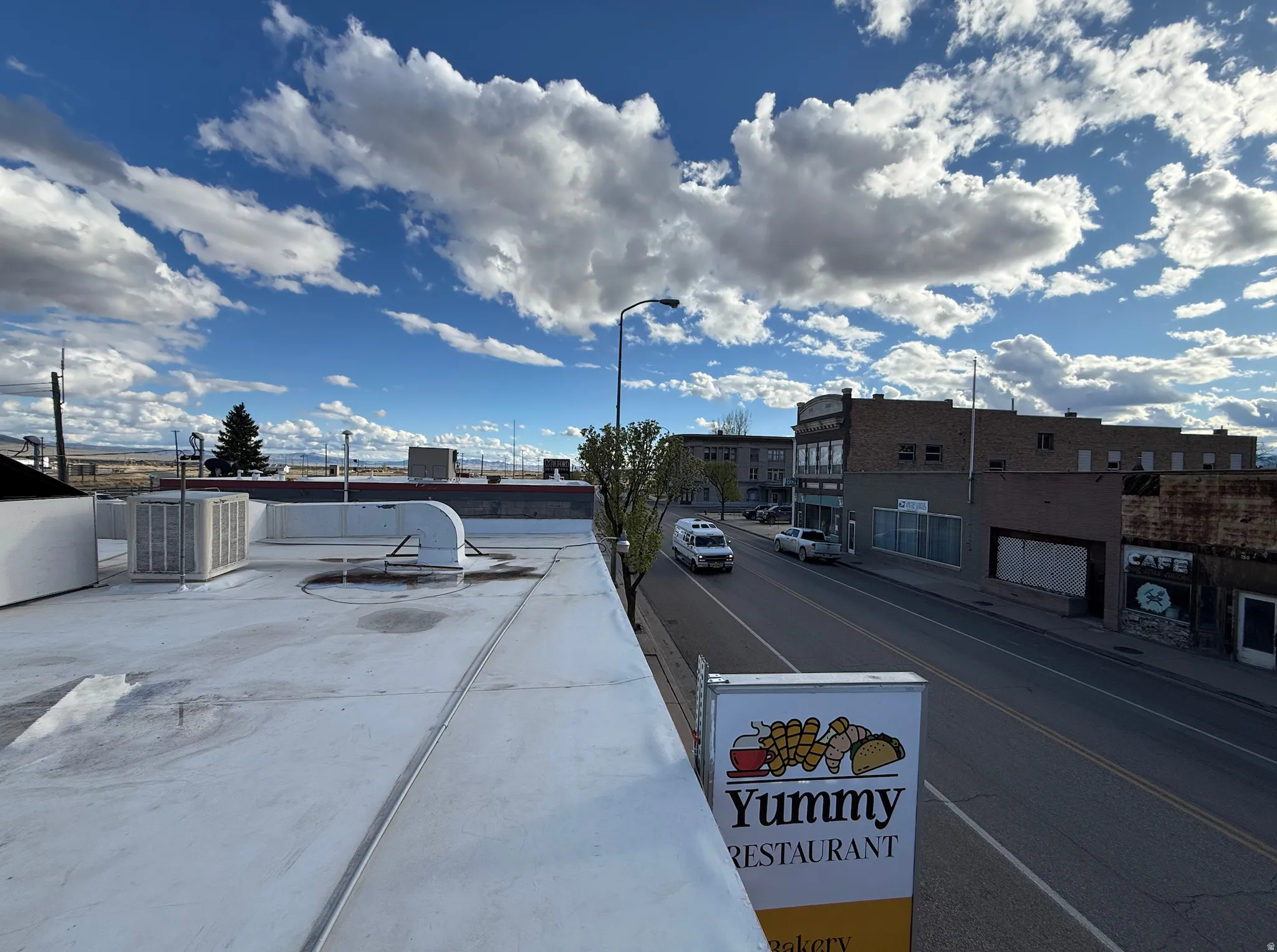 View of asphalt street featuring street lights, sidewalks, and curbs