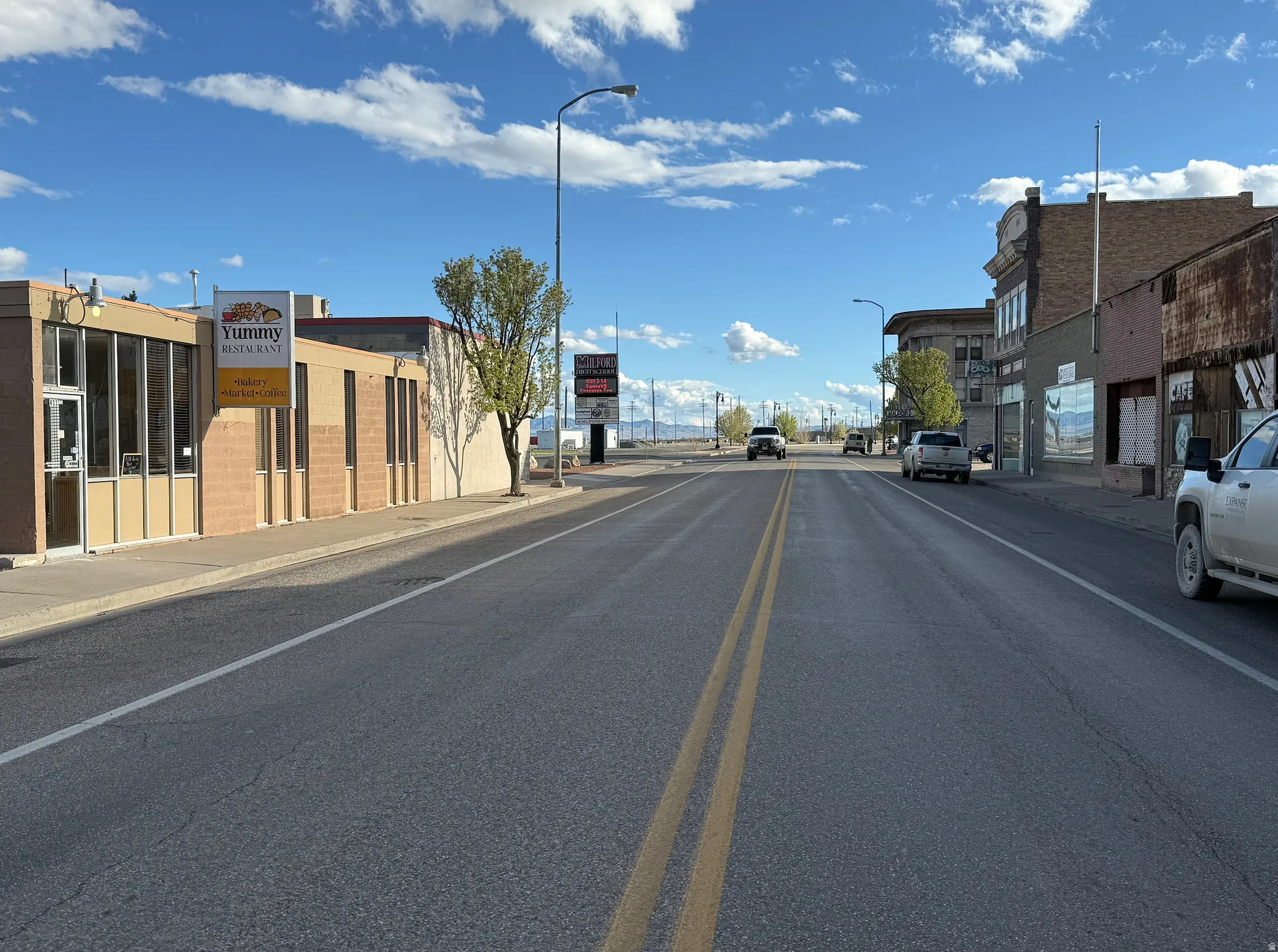 View of asphalt street featuring sidewalks, curbs, and street lighting