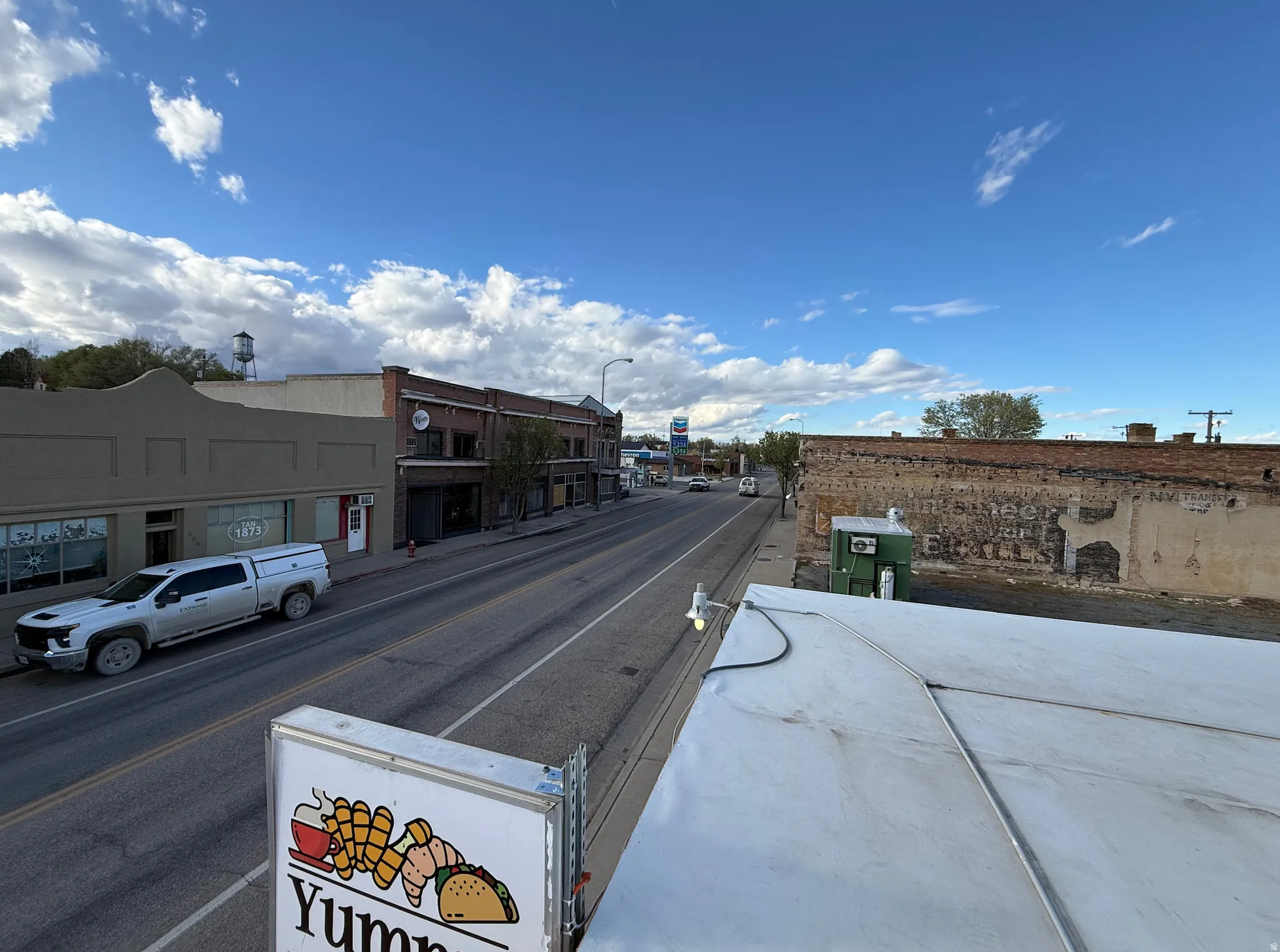 View of asphalt road featuring street lights, curbs, and sidewalks
