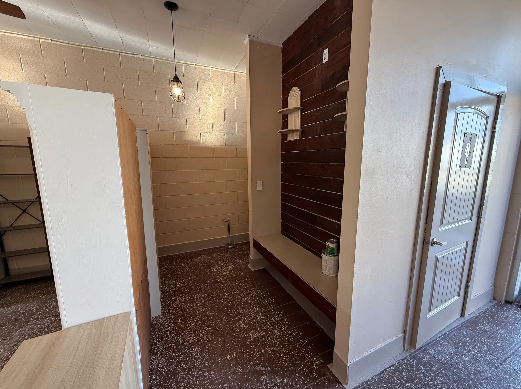 Corridor featuring concrete block wall and dark flooring