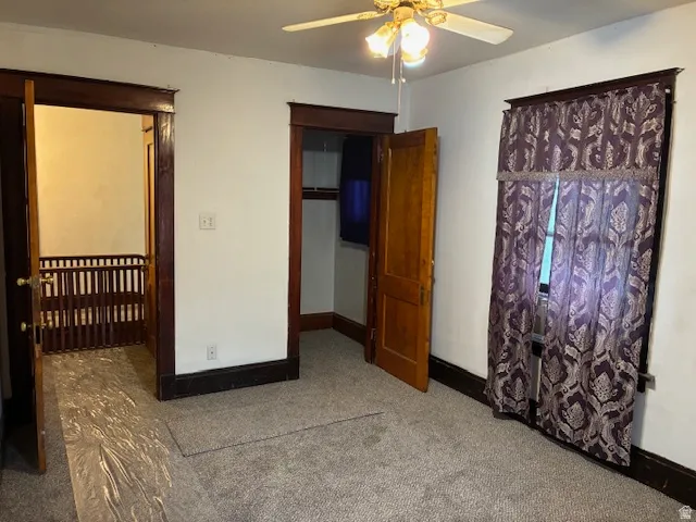 Unfurnished bedroom featuring light colored carpet, ceiling fan, and a walk in closet