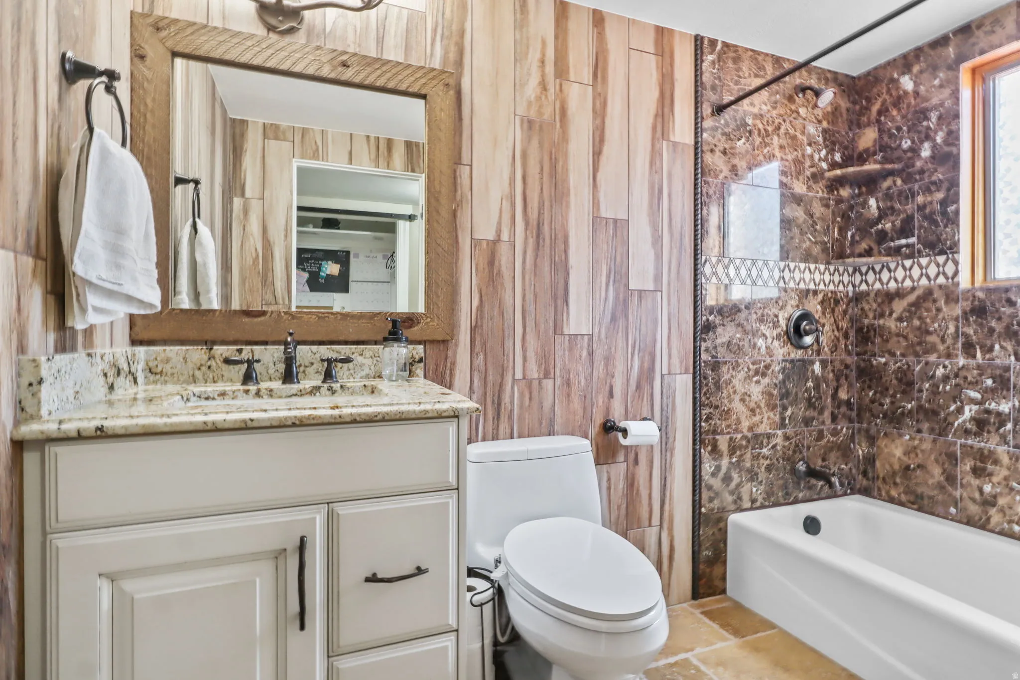 Bathroom featuring  shower combination, vanity, and tile walls