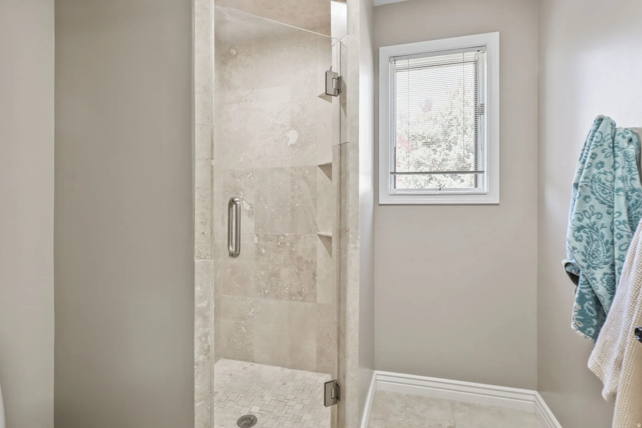Bathroom with a shower stall and light tile patterned floors