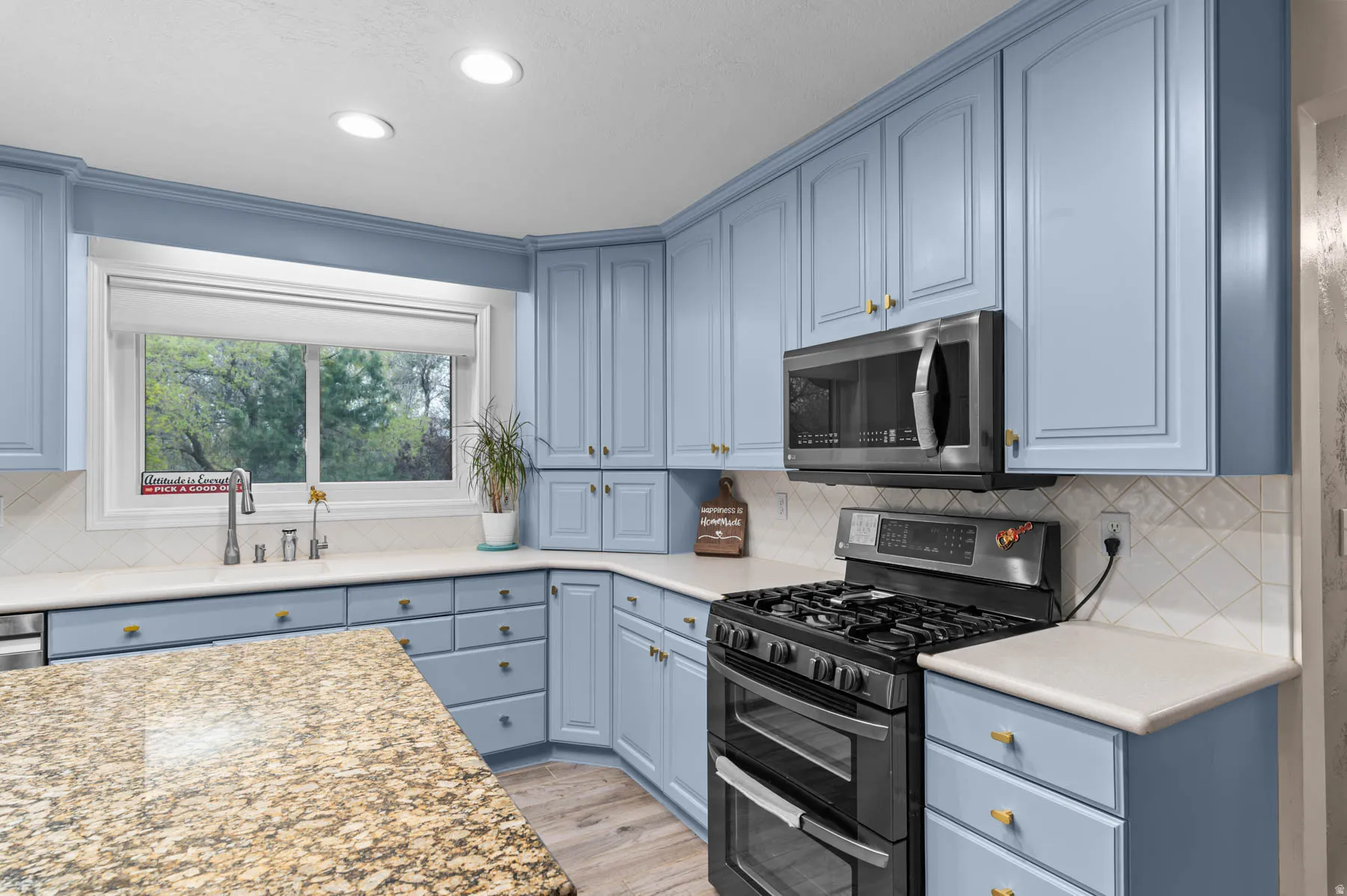 Kitchen featuring stainless steel appliances, blue cabinetry, light wood-style floors, decorative backsplash, and recessed lighting