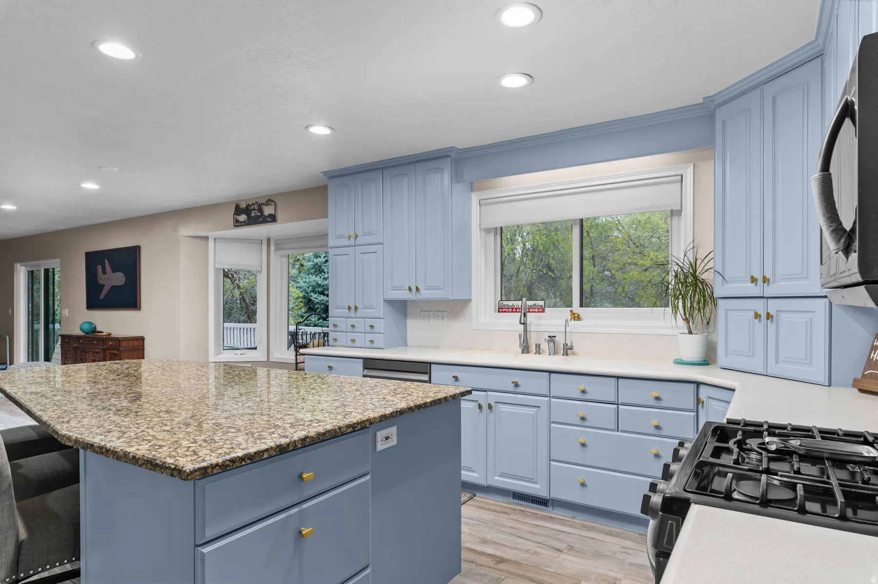 Kitchen featuring blue cabinets, stainless steel appliances, tasteful backsplash, light wood finished floors, and a kitchen island