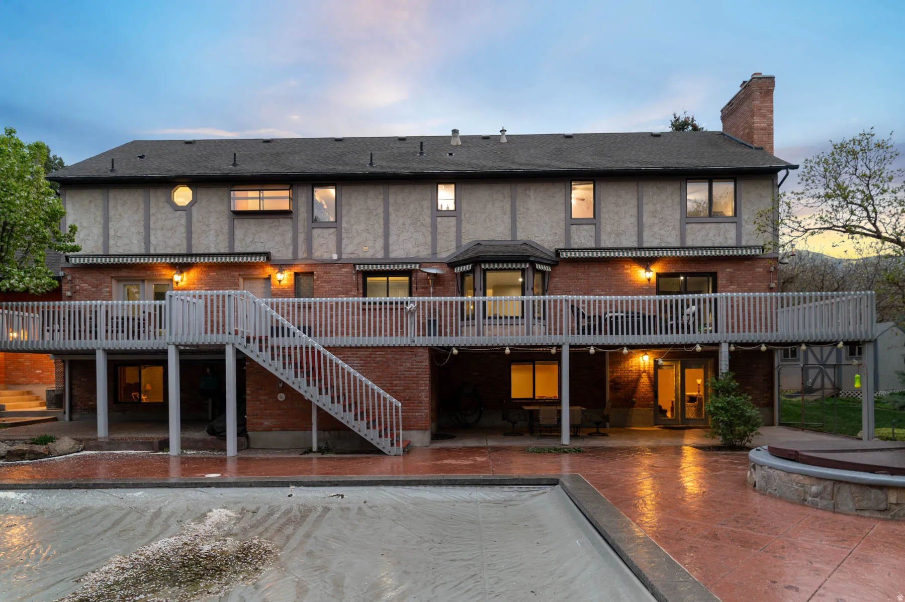 Back of house featuring a patio, a chimney, and brick siding