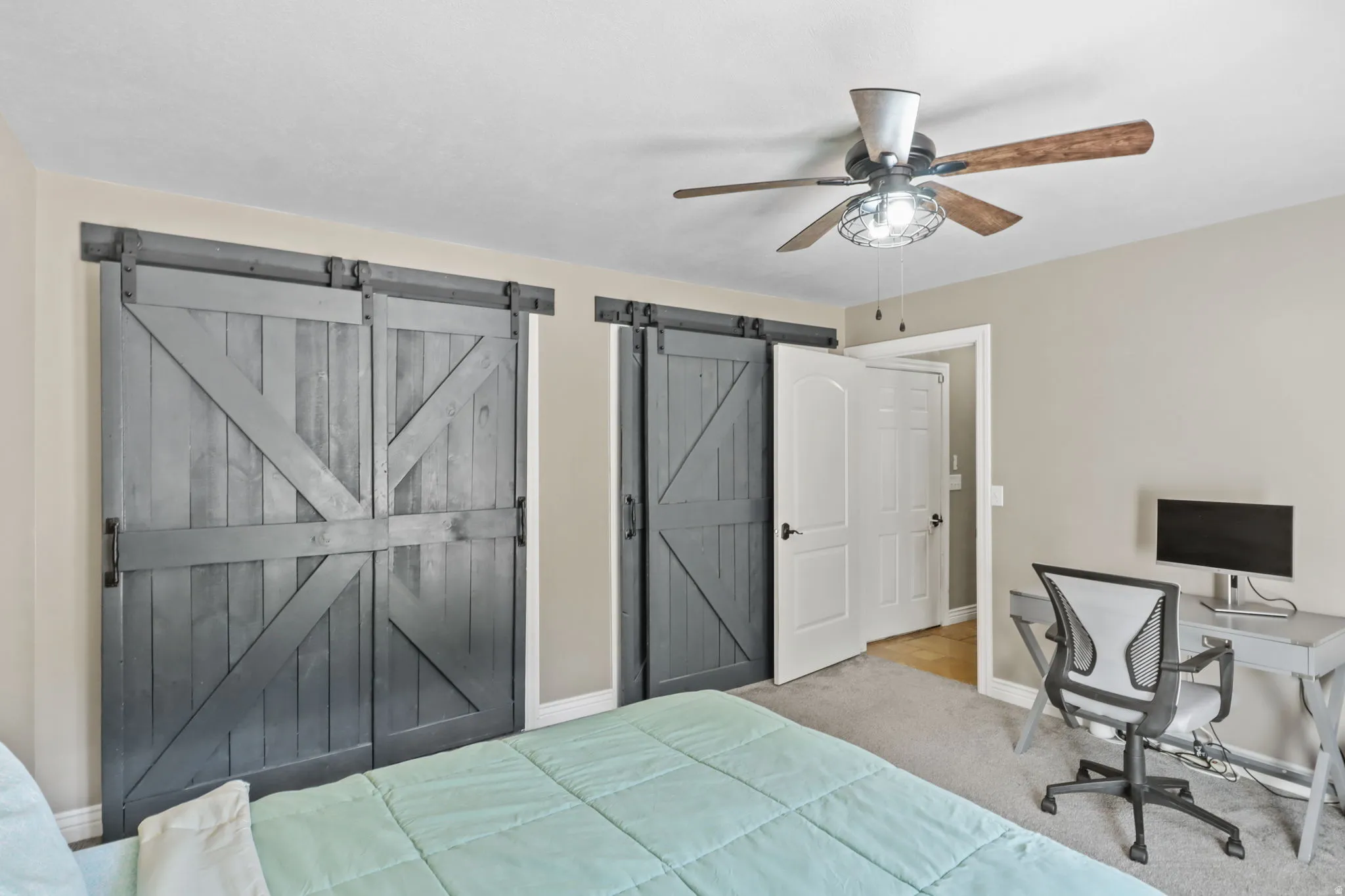Bedroom featuring ceiling fan, a barn door, carpet floors, and an office area