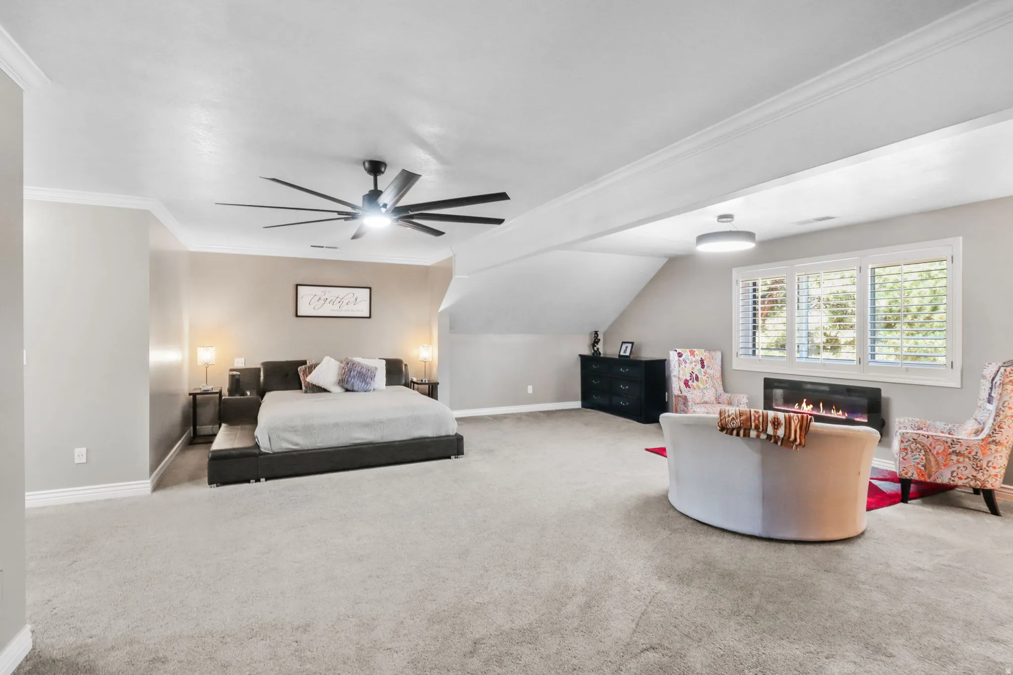 Carpeted bedroom featuring crown molding, a glass covered fireplace, and a ceiling fan