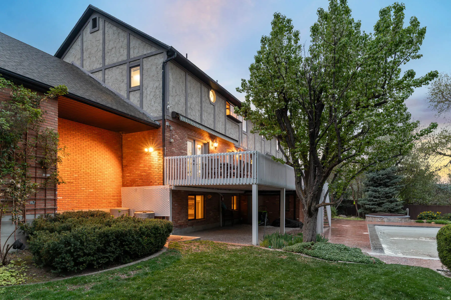 Back of house with a patio area, a deck, a yard, and brick siding