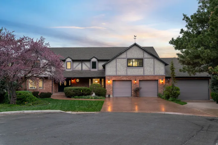Tudor home with covered porch, a shingled roof, driveway, and brick siding