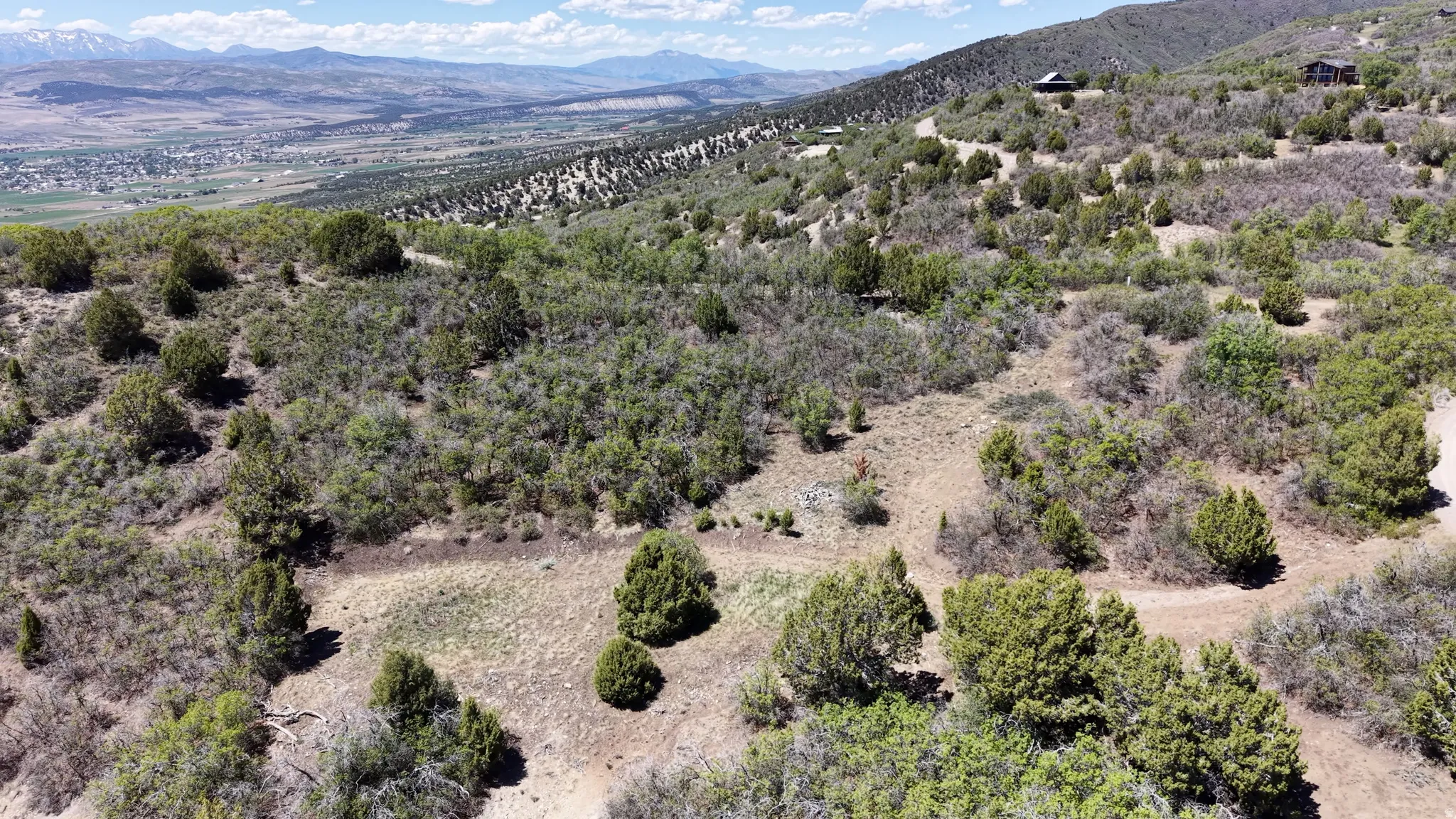 Expansive undeveloped land featuring diverse natural vegetation, distant mountain ranges, and a broad valley