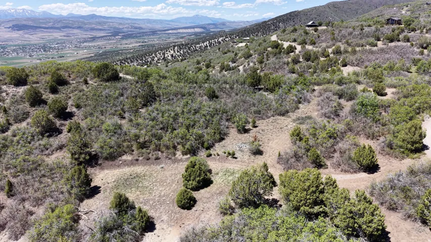 Expansive undeveloped land featuring diverse natural vegetation, distant mountain ranges, and a broad valley