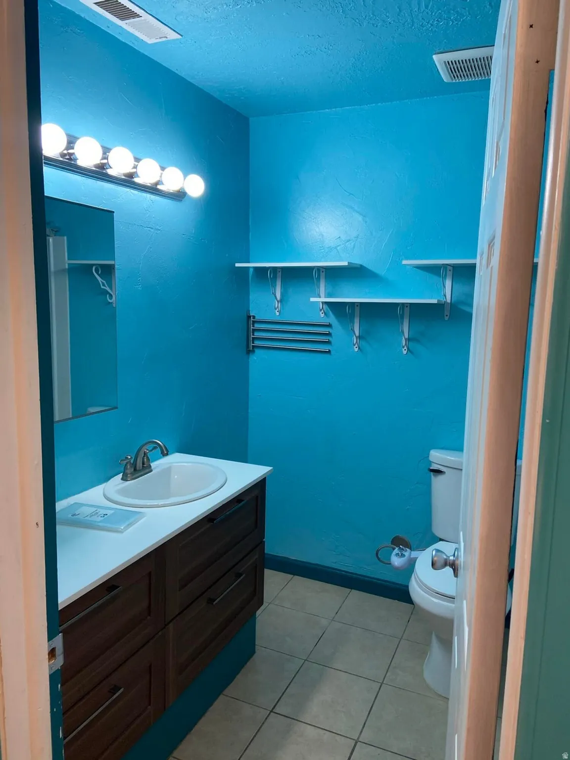 Bathroom featuring vanity, light tile patterned flooring, and a textured ceiling