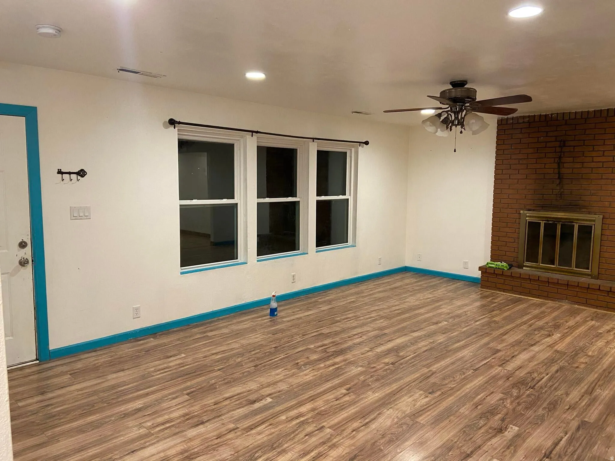 Unfurnished living room featuring ceiling fan, dark wood-style flooring, a brick fireplace, and recessed lighting