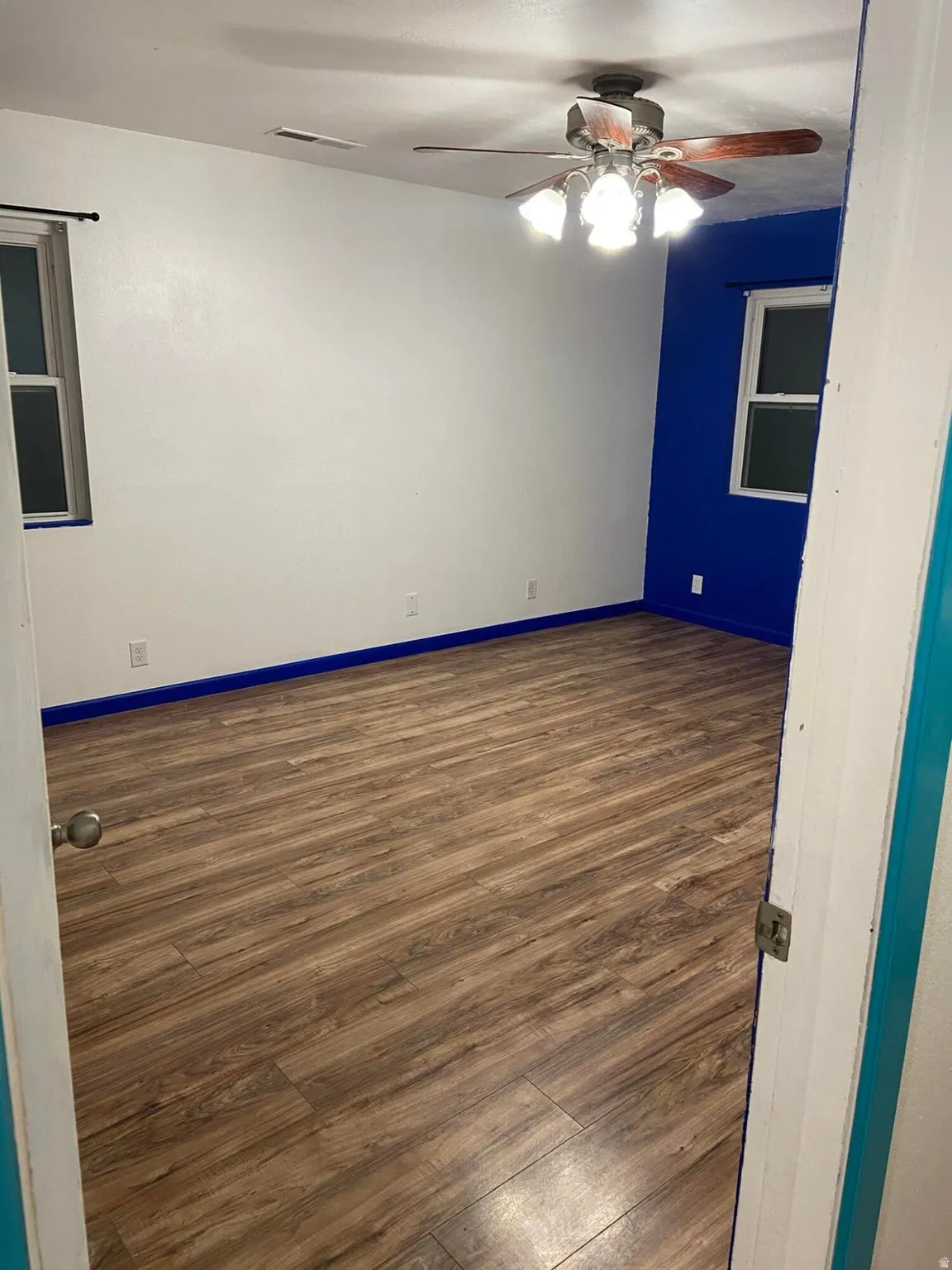 Empty room featuring dark wood-style floors and ceiling fan