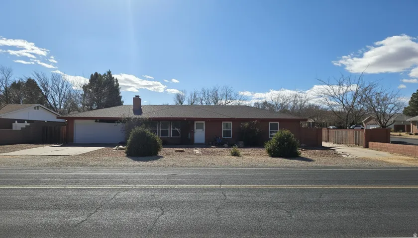 Ranch-style home with an attached garage, concrete driveway, and a chimney